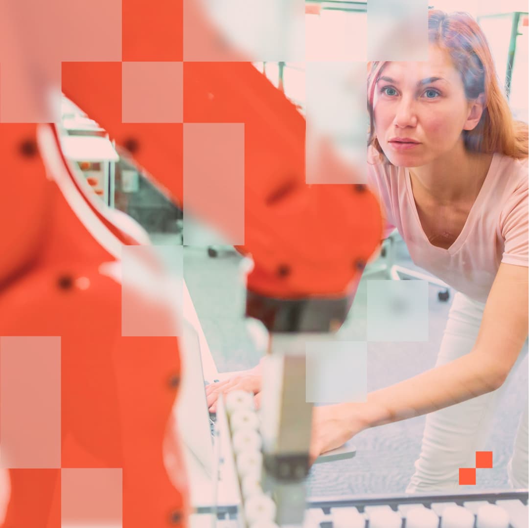 Eine Frau mit konzentriertem Gesichtsausdruck arbeitet an einem großen orangefarbenen Industrieroboter. Sie befindet sich in einem modernen Labor oder Büro, umgeben von hellen Möbeln und Computern. Ihre Hände sind in Bewegung, während sie den Roboter bedient oder überwacht.