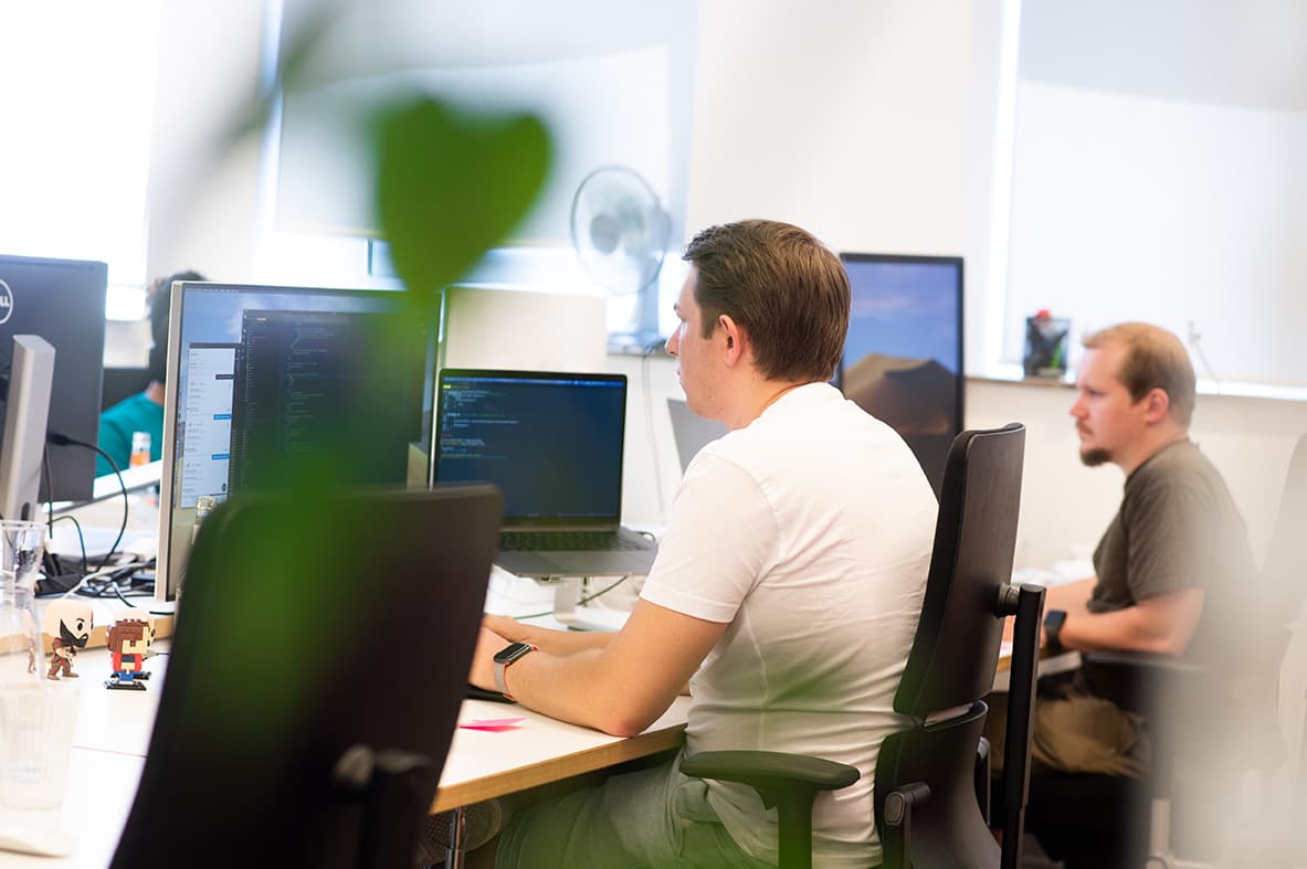 Zwei Kollegen aus dem Development im Bielefelder Büro bei der Arbeit an ihren Bildschirmen. u+i interact