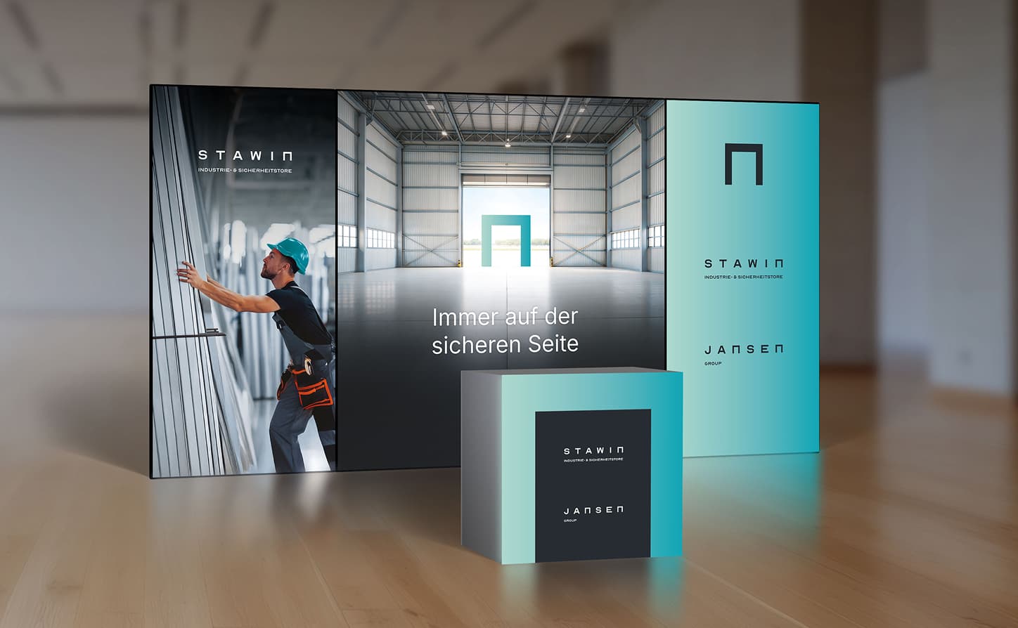 Trade show display with a large backdrop featuring a worker in a safety harness, company logos "STAWIN" and "JANSEN," and the text "Immer auf der sicheren Seite."