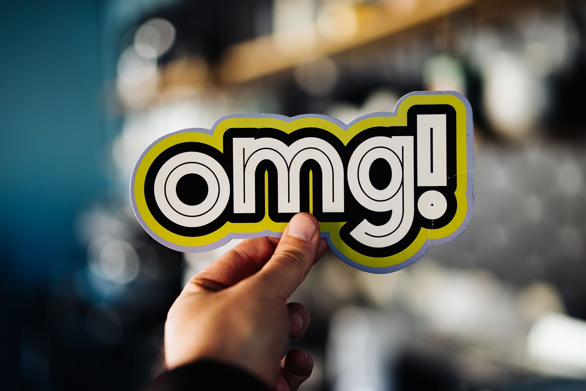 Die Hand eines+einer Kolleg+in hält im Büro ein witziges Schild in die Kamera: "omg!". u+i interact: 