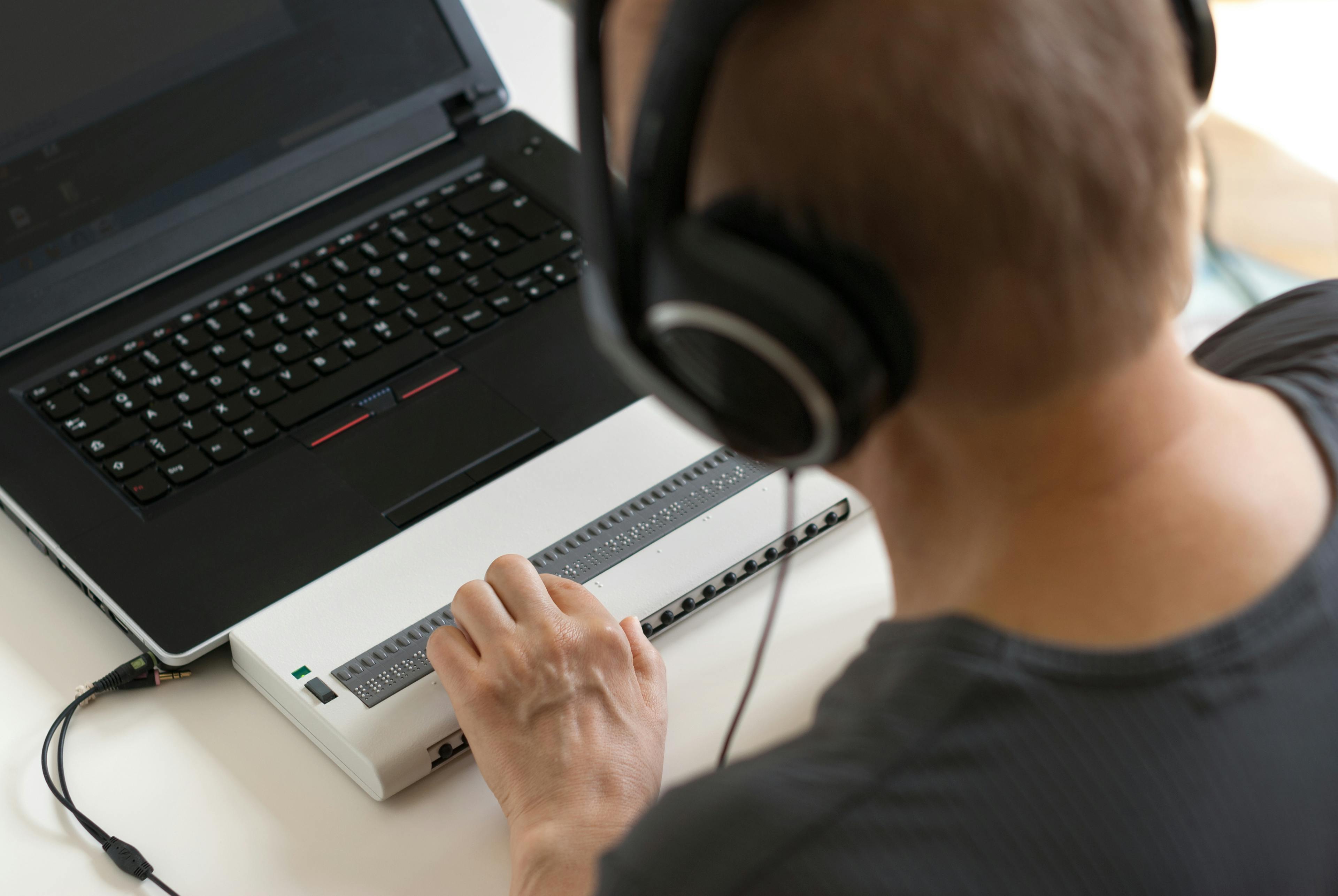 Blinde Person arbeitet am Computer mit einer Brailletastatur