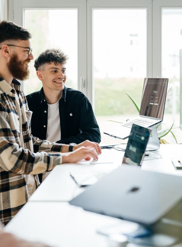 Zwei Personen schauen konzentriert auf einen Laptop